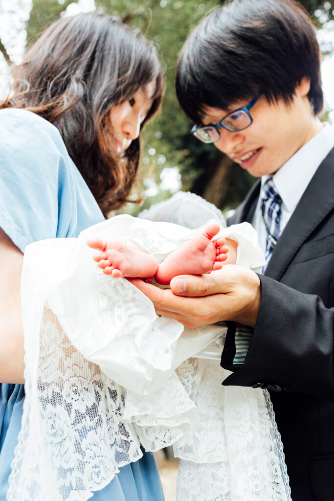 両親の手のひらにのせた赤ちゃんの足