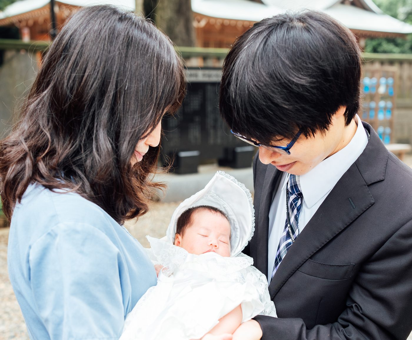神社でのお宮参り。白い産着の赤ちゃんを抱くご両親